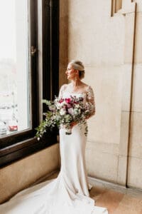 Bride looking out large, beautiful window.