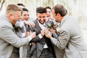 Groom laughing with his groomsmen during wedding day photos.