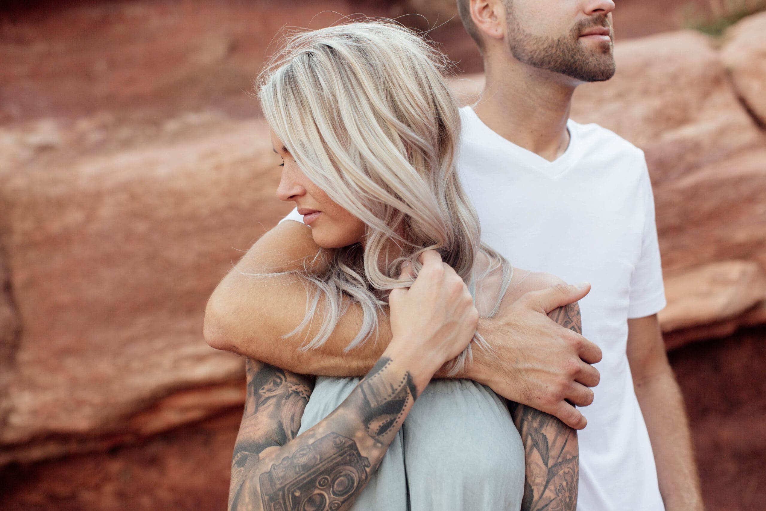 Couple standing close together in front of red rocks at Garden of the Gods, Colorado Springs.