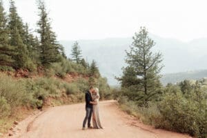 Engaged couple walking down a deserted road at Garden of the Gods, surrounded by red rock formations. 
