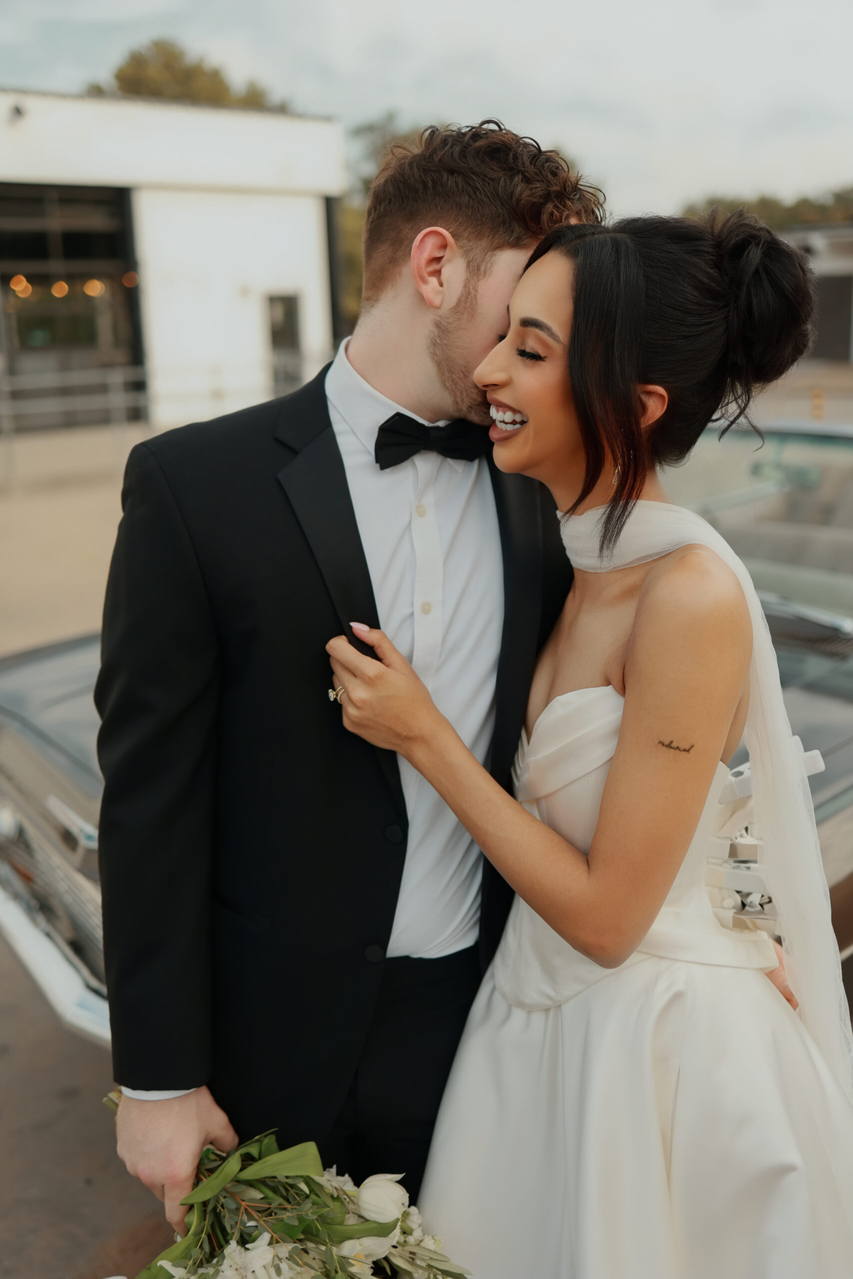 Bride and groom in front of car at wedding