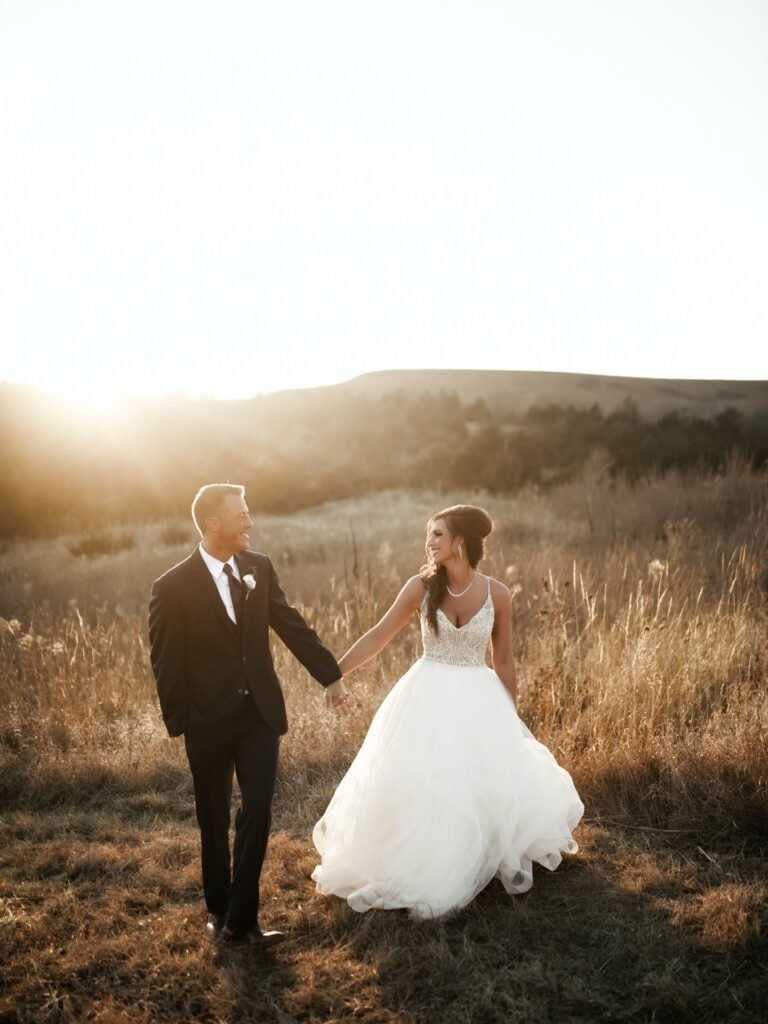 birde and groom walking in field in front of mountains