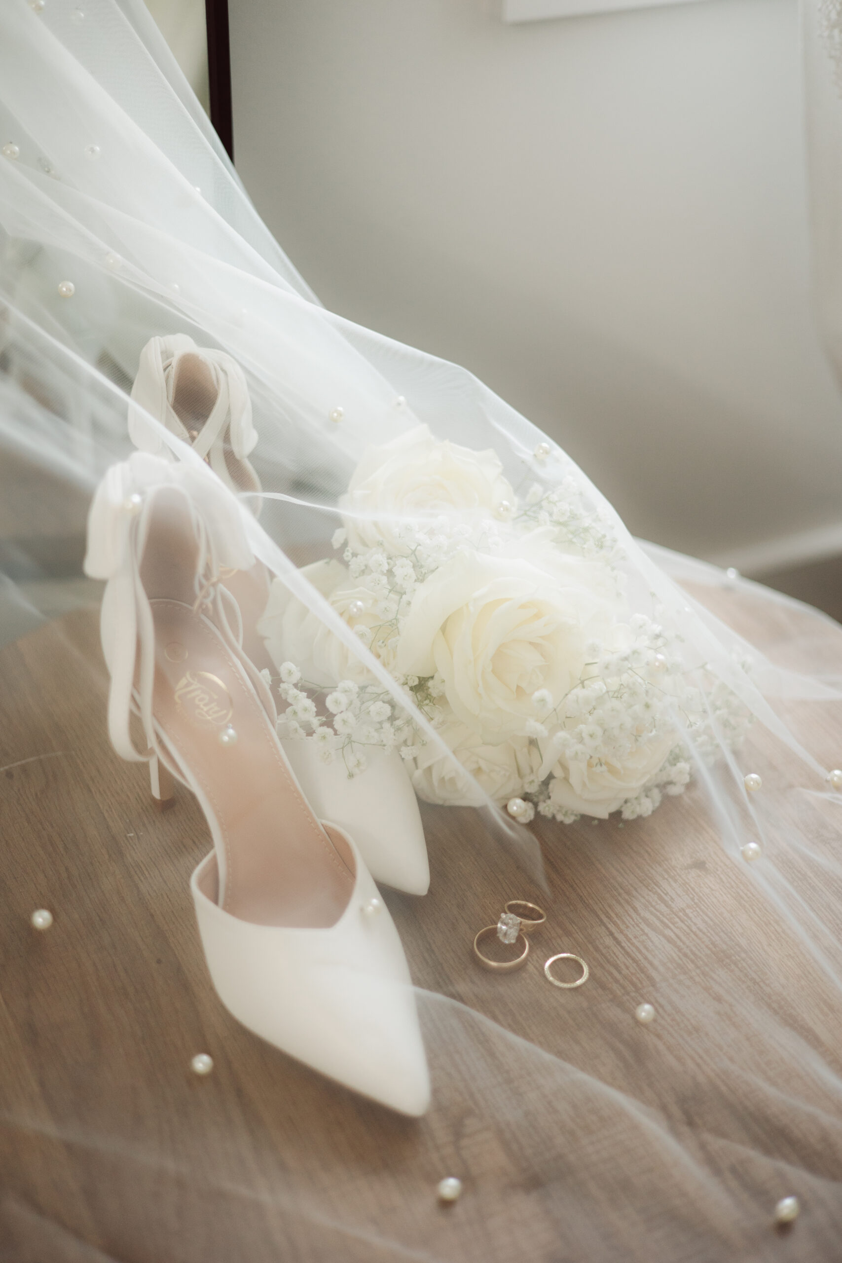 Bridal veil, shoes and flowers sitting on a chair.