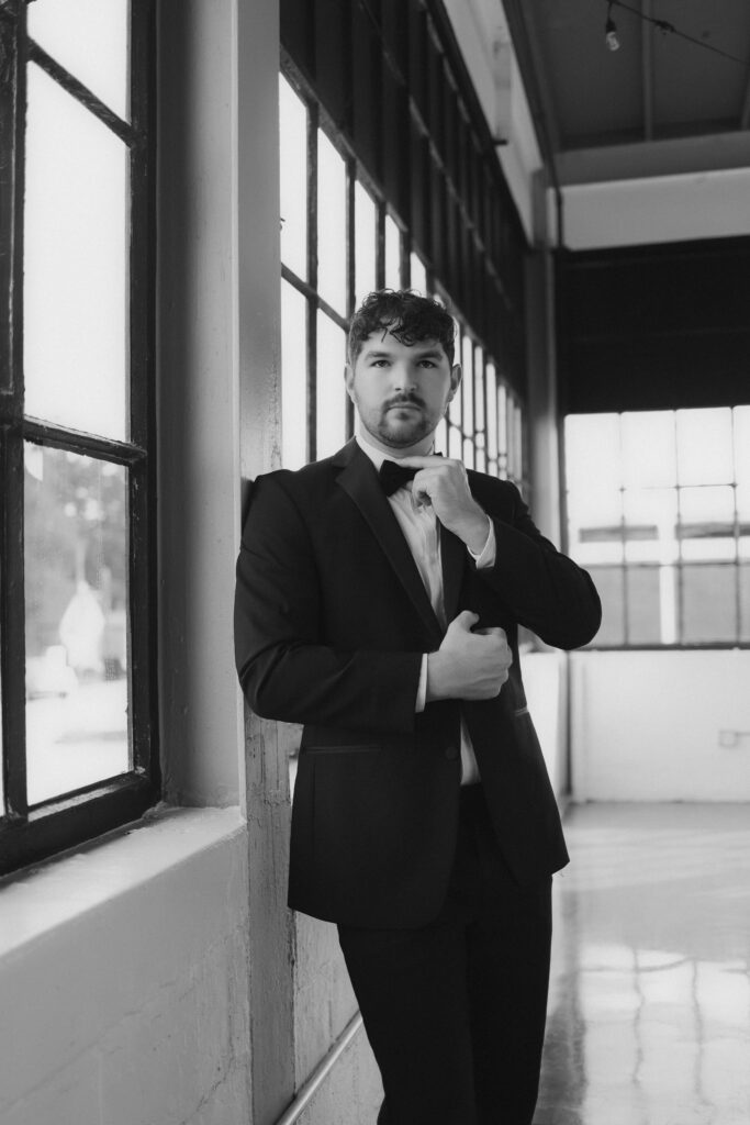 Black and white groom portrait adjusting bow tie captured by Atlanta luxury wedding photographer