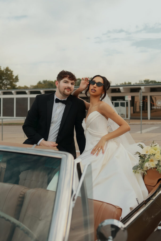 Stylish bride and groom posing in vintage convertible on wedding day captured by Atlanta luxury wedding photographer