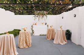 Outdoor ceremony setup at The Carlyle Atlanta wedding venue featuring floral arch, draped cocktail tables, and greenery ceiling installation in Buckhead Georgia