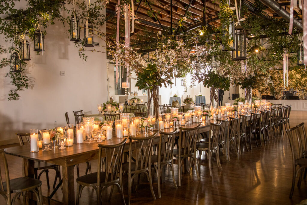 Elegant candlelit reception setup at The Carlyle Atlanta wedding venue featuring long wooden tables, greenery installations, and romantic lighting in Buckhead, Georgia