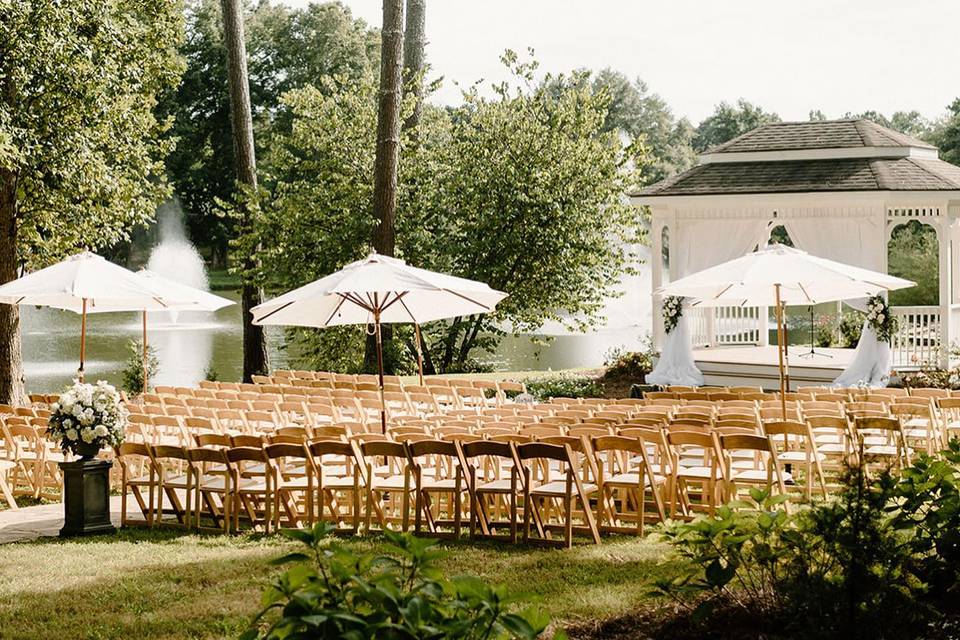 Outdoor ceremony setup at Little River Farms wedding venue featuring lakeside gazebo, white florals, and elegant chairs in Alpharetta Georgia