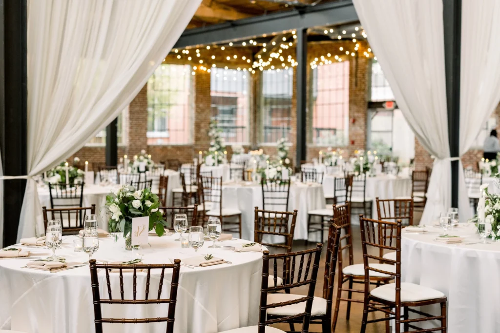 Reception setup at The Foundry at Puritan Mill wedding venue featuring exposed brick walls, string lights, and elegant round tables in Atlanta Georgia